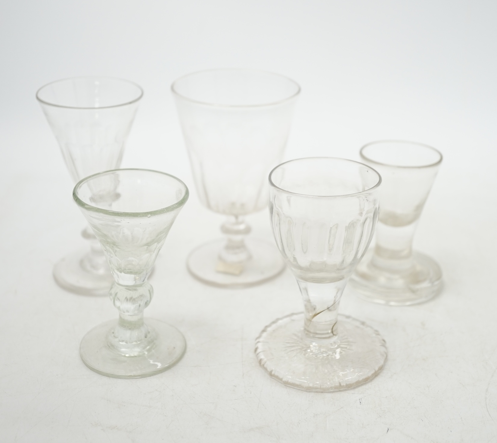 A mid 18th century wine glass with over-sewn foot and four others, three with knopped stems, tallest 10.5cm. Condition - good